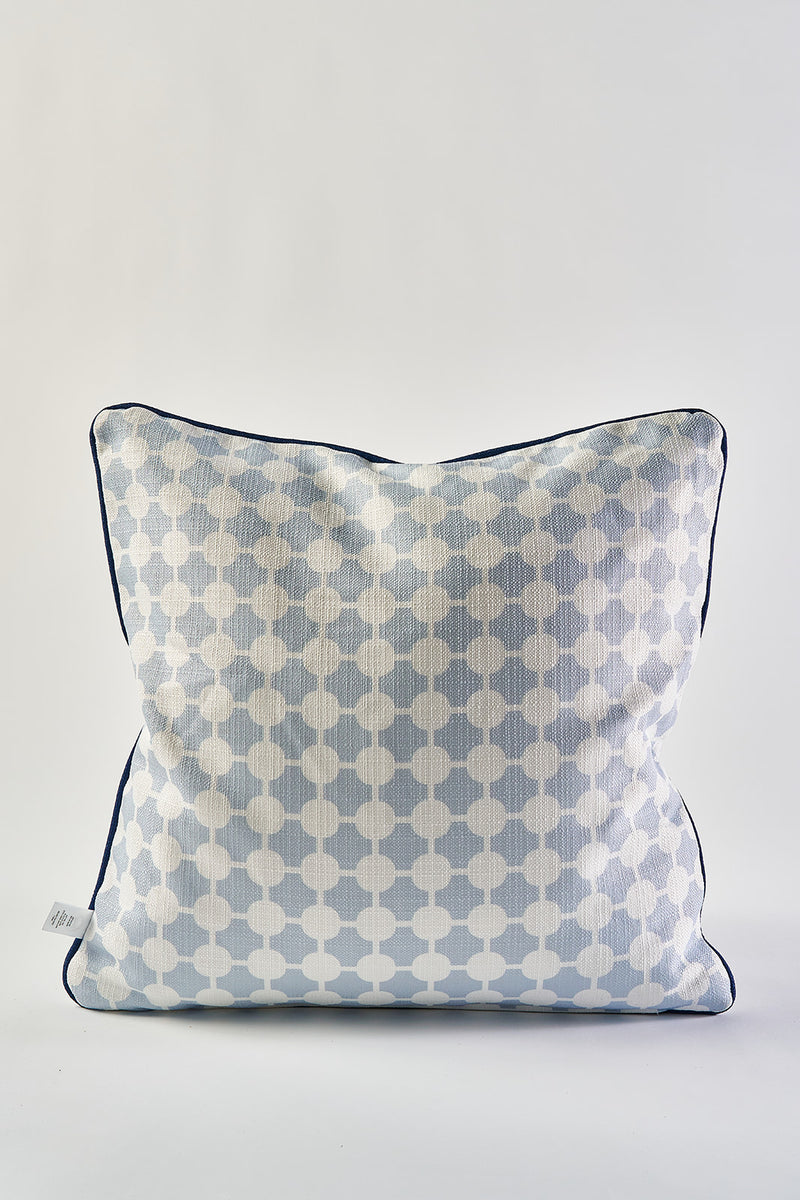 The Oversized Mod Dot Grid Pillow is a square decorative accent inspired by modern Southern decor, featuring a light blue and white geometric hand-drawn pattern, piped edges, and a small fabric tag on the side against a plain white background.