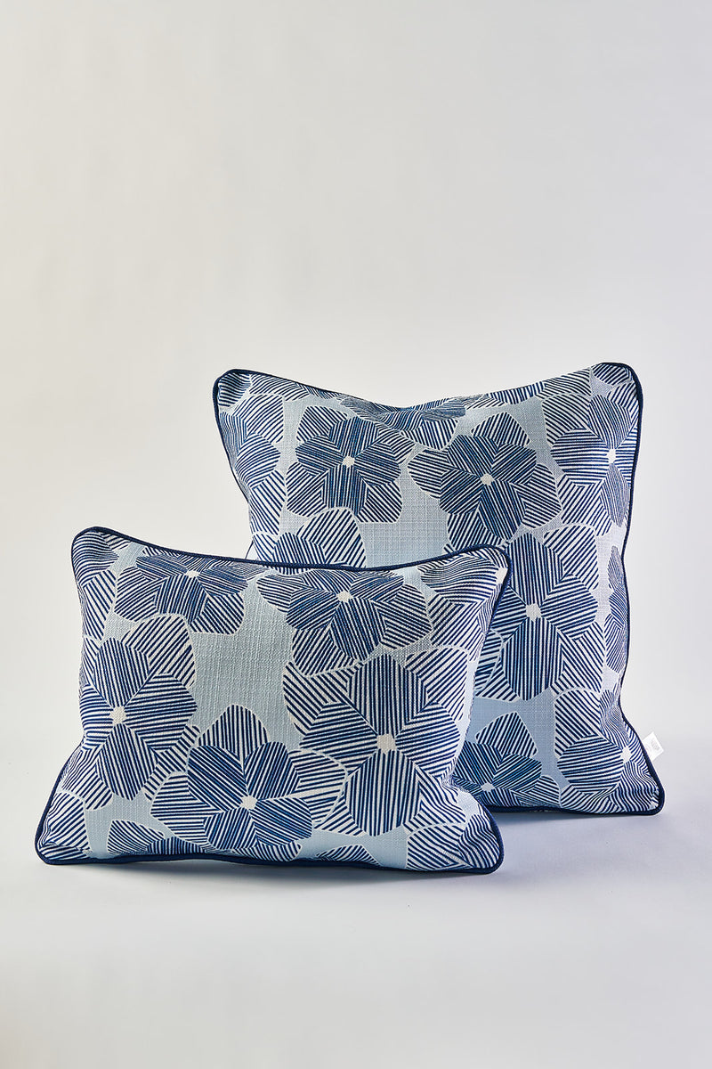 Two Mod Flora Lumbar Pillows in blue and white, featuring large stylized floral patterns inspired by Southern decor, are arranged on a plain light background with one pillow slightly in front of the other.