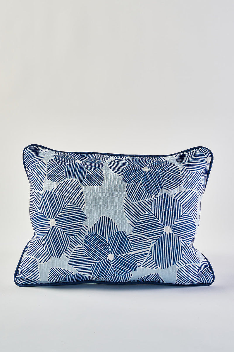 The Mod Flora Lumbar Pillow boasts bold blue striped petals and dark piping on a crisp white background, adding modern Southern flair to any space.