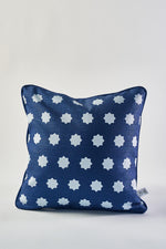 The Mod Stars Pillow is square and navy blue with evenly spaced white star shapes. It features a small fabric tag on the right side and is shown against a plain white background.