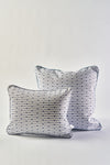 Two white accent pillows inspired by the Mod Mini Crossing Tiles Lumbar Pillow, featuring blue and black geometric dot and line patterns with blue piping, are placed together on a plain white background. The larger pillow sits slightly behind the smaller one.