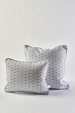 Two white accent pillows inspired by the Mod Mini Crossing Tiles Lumbar Pillow, featuring blue and black geometric dot and line patterns with blue piping, are placed together on a plain white background. The larger pillow sits slightly behind the smaller one.