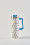 The Mini Calico 30oz Tumbler, with a blue handle and circular pattern, features stainless steel construction, a transparent lid, reusable straw, and no-sweat exterior—displayed on a plain white background.