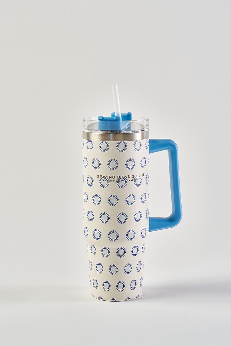 The Mini Calico 30oz Tumbler, with a blue handle and circular pattern, features stainless steel construction, a transparent lid, reusable straw, and no-sweat exterior—displayed on a plain white background.