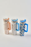 Three Mini Calico 30oz Tumblers with handles, each featuring vibrant patterns and matching straws, are lined up on a white background. These stainless steel cups have insulated, no-sweat exteriors that keep hands dry.