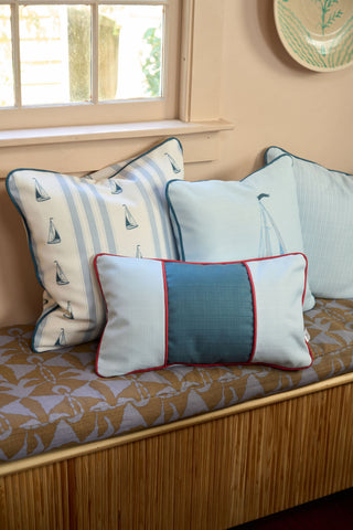 Three decorative pillows, including the Stripes of the Union Extended Lumbar Pillow, are arranged on a cushioned window bench with a patterned seat in a cozy, well-lit room.