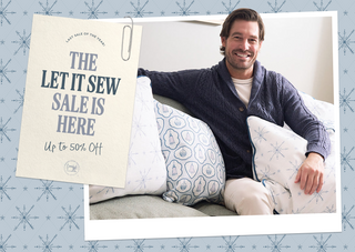 Man sitting on a couch with decorative pillows, promotional sign for 'The Let It Sew Sale' in the corner.