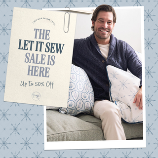 Man holding pillows with a promotional sign for 'The Let It Sew Sale' on a decorative background.