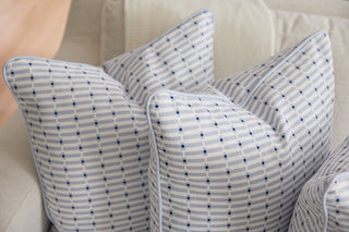 Three Oversized Mod Mini Crossing Tiles in Blue Pillows, featuring a blue and white striped pattern with small blue crosses, are arranged on a light sofa—soft, stylish accents ideal for bringing charm to Southern home decor.