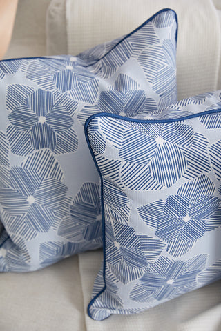 Two Oversized Mod Flora Pillows from Sewing Down South, featuring blue and white floral stripes with dark blue piping, are arranged on a light fabric sofa or chair.