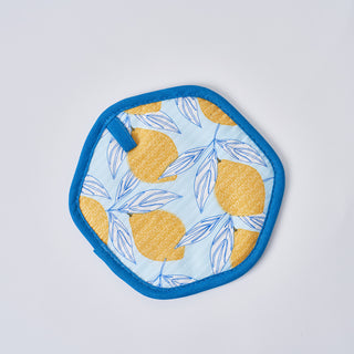 The Lots of Lemons Pot Holder is a stylish, heat-resistant hexagonal fabric coaster with a blue border, adorned with yellow lemons and blue leaves on a light blue background.