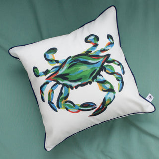 The Outdoor King Crab Pillow with Navy showcases a vibrant crab design in green, blue, and orange on white. Made from water-resistant SDS Shield® Outdoor Fabric, it features dark piping on the edges and sits beautifully on a green fabric surface.