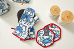 Introducing the Crab Craze collection: vibrant crab-patterned oven mitt and Pot Holder with silicone grip for superior heat resistance, shown on a white surface next to two textured white jars with wooden lids.
