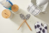 A baking scene features flour on a white surface, two SDS Spatulas with black polka dots, a cloth, covered jars, baking mix, polka-dotted oven mitts, a mixer, and nonstick cookware.