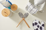 A baking scene features flour on a white surface, two SDS Spatulas with black polka dots, a cloth, covered jars, baking mix, polka-dotted oven mitts, a mixer, and nonstick cookware.