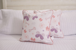 The Kids Collection: Butterfly Pillow features pink and purple butterfly motifs on a white quilted bedspread, enhanced by a white background with pink piping for a cozy room touch.