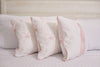 Three Kids Collection: Bow & Ballet Pillows, featuring pink ballet shoe and bow designs with pink piping, adorn a bed with a white quilted bedspread. Inspired by a Sewing Down South® pattern, they add elegance to the cozy arrangement.