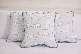 Three decorative pillows from the Kids Collection: Transportation Pillow feature playful car, train, boat, and helicopter outlines in light blue on white. They rest on a crisp white quilted surface with the Sewing Down South® pattern.