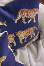 The On The Prowl Midnight Pillow showcases tigers in various poses against a blue backdrop, adding an exotic touch to any space with its animal pattern design.